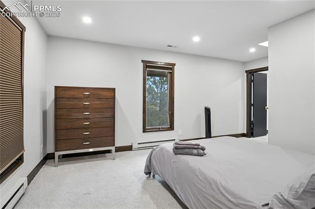 Bedroom with recessed lighting, light colored carpet, and a baseboard heating unit