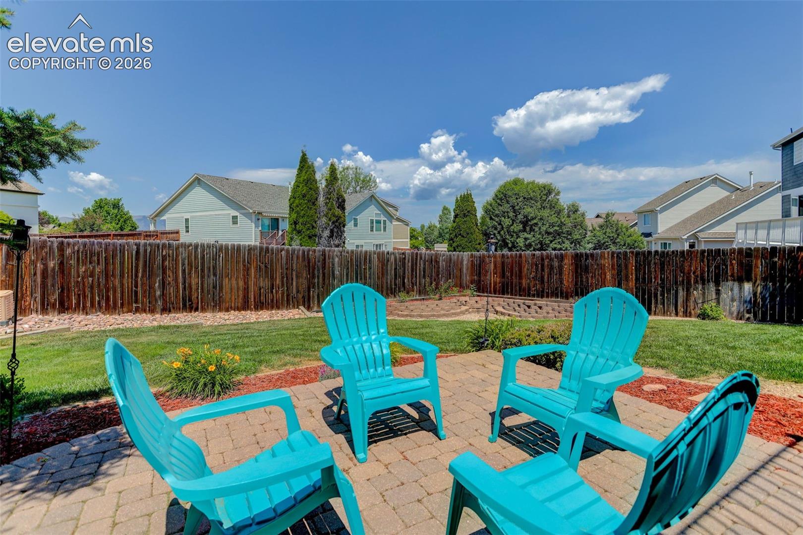 Backyard patio featuring paver stone flooring, a surrounding wood privacy fence, and a manicured lawn
