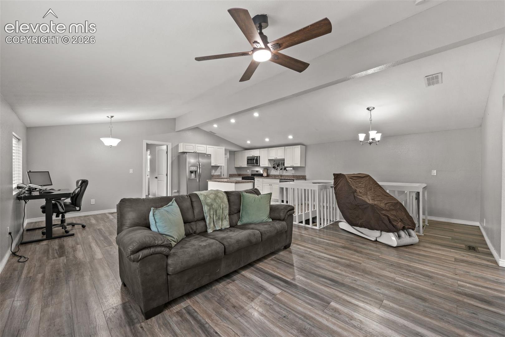 Open-concept interior featuring vaulted ceilings, wood-finish flooring, recessed lighting, and a ceiling fan with integrated light fixture