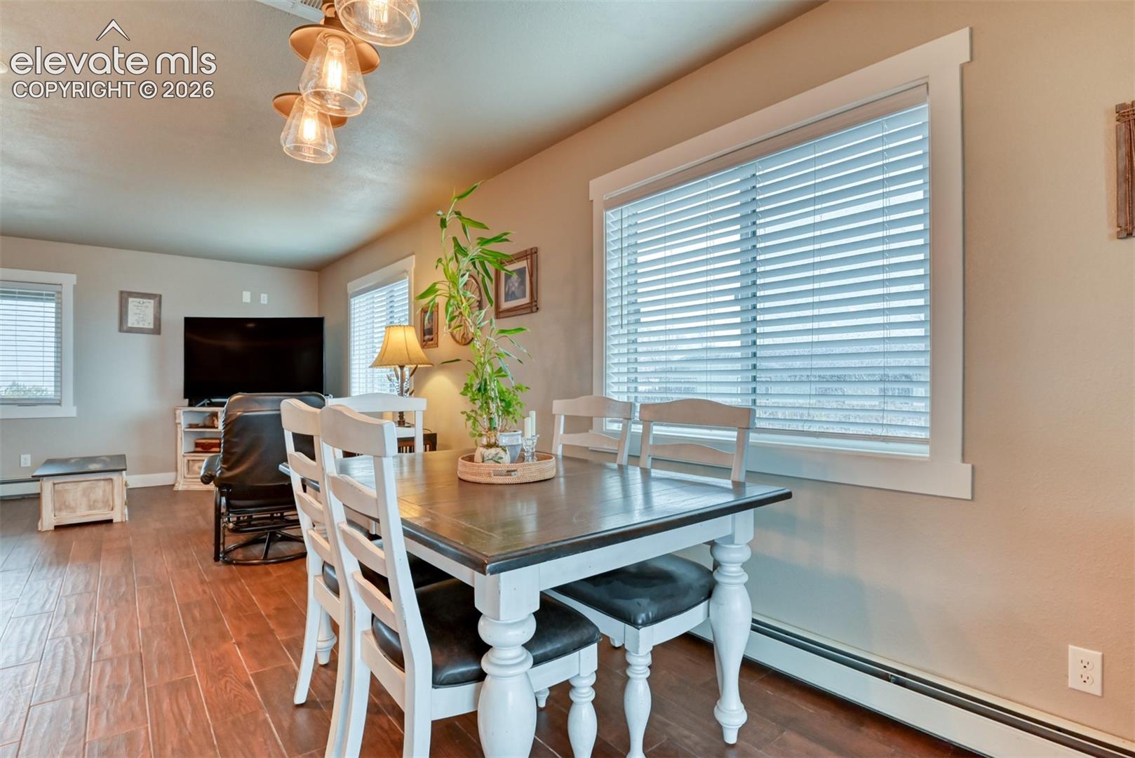 Dining area with a baseboard heating unit and dark wood-style floors