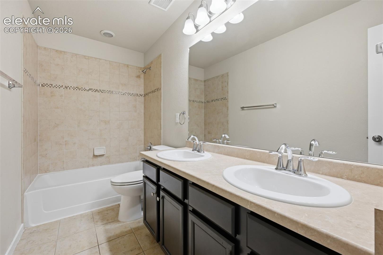 The upper-level hall bath features dual sinks and a tiled tub-and-shower surround.