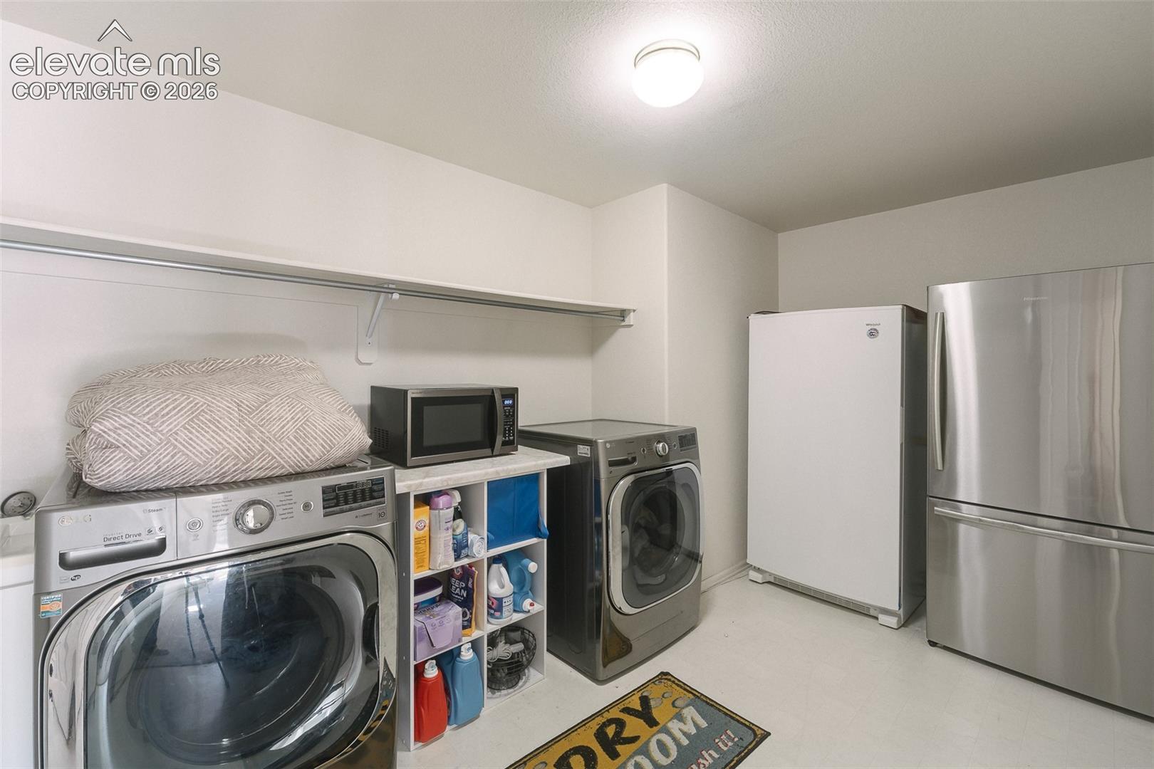 Basement Laundry Room with built-in shelf, washer, dryer, stand up freezer, and stainless steel refrigerator that stays.