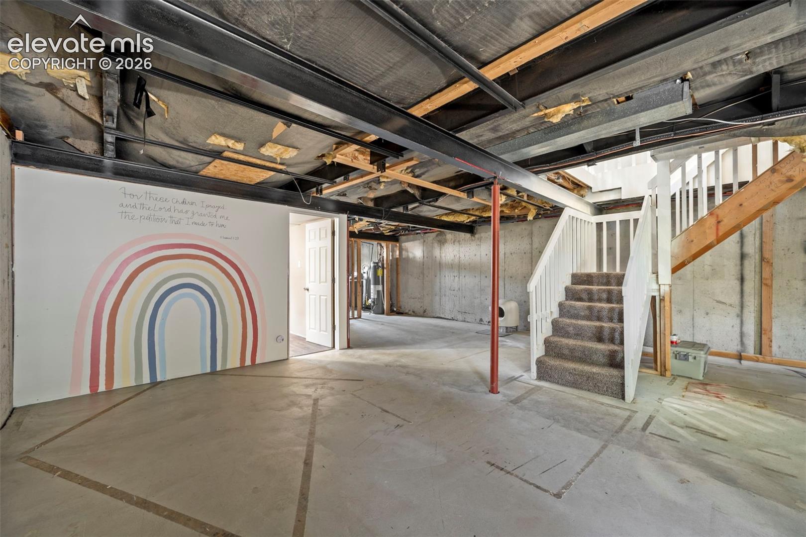 Unfinished lower level featuring concrete foundation walls, exposed steel support beams, concrete flooring, and wooden staircase with white balusters