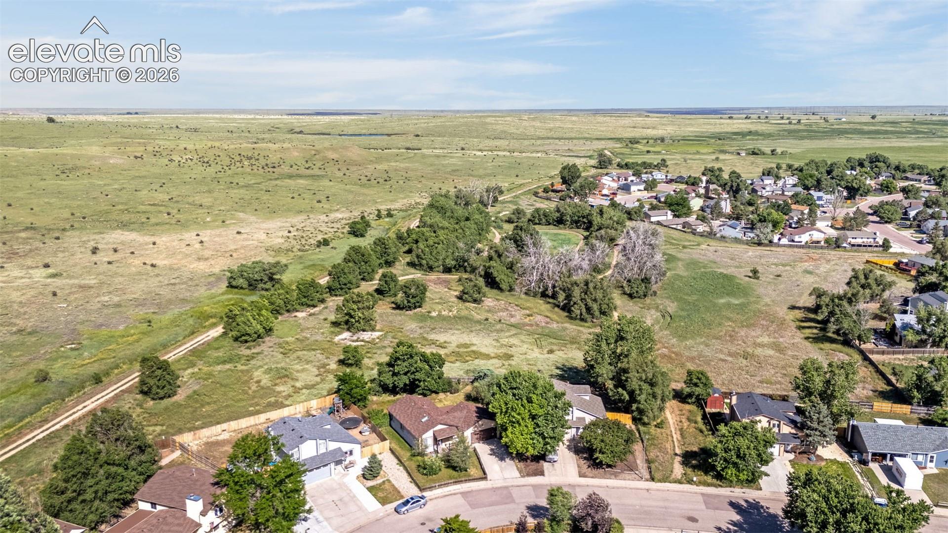 Aerial perspective featuring expansive open land, mature clusters of trees, and established residential lots