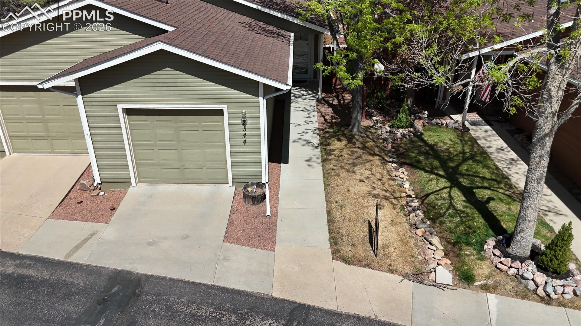 The property features a concrete driveway and walkway, leading to a garage with a textured door