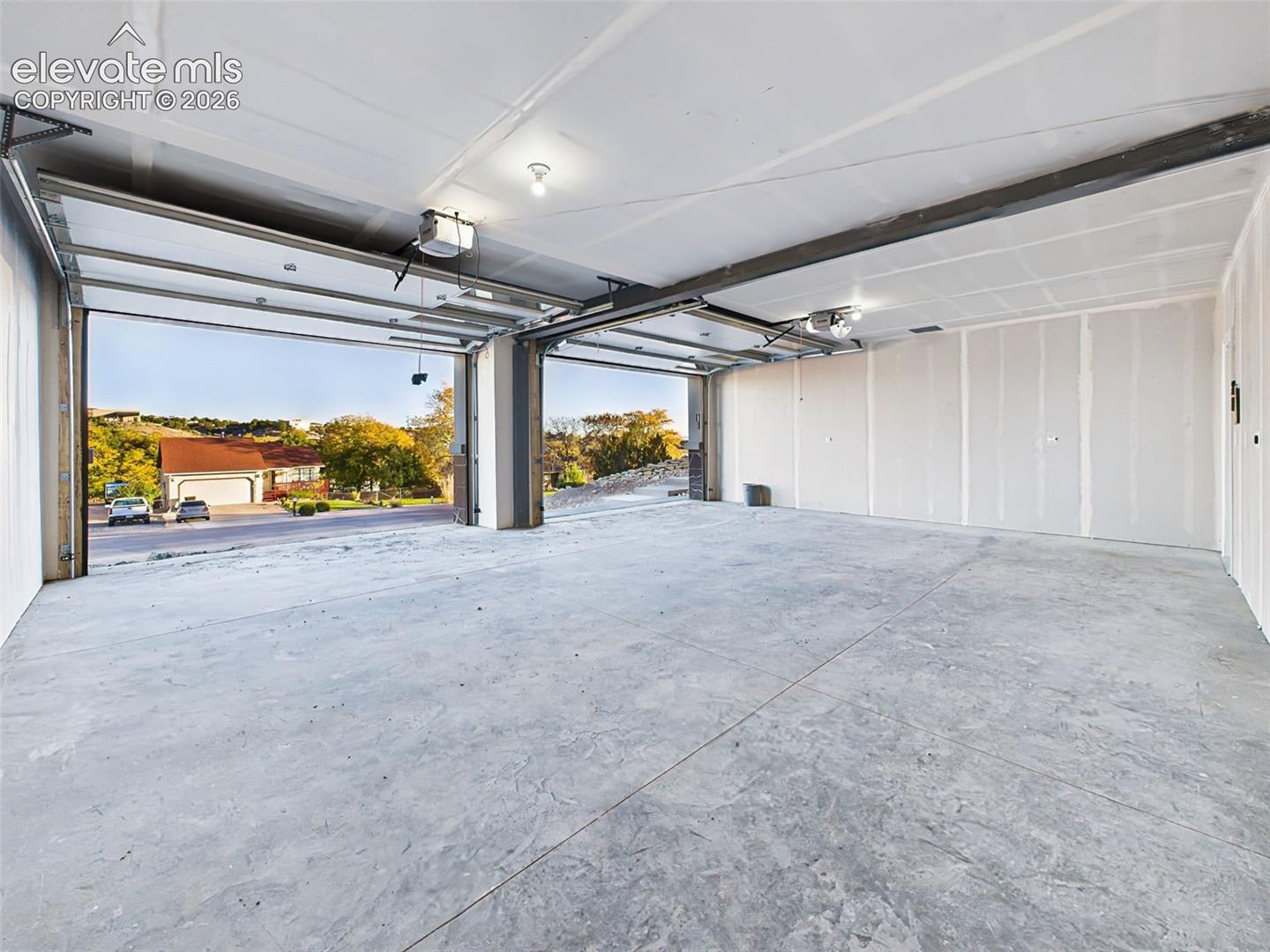 Massive finished 21' x28' garage with high ceilings and room for vehicles, storage, or workshop setup, with insulated 8' x 12' garage doors and smart openers.