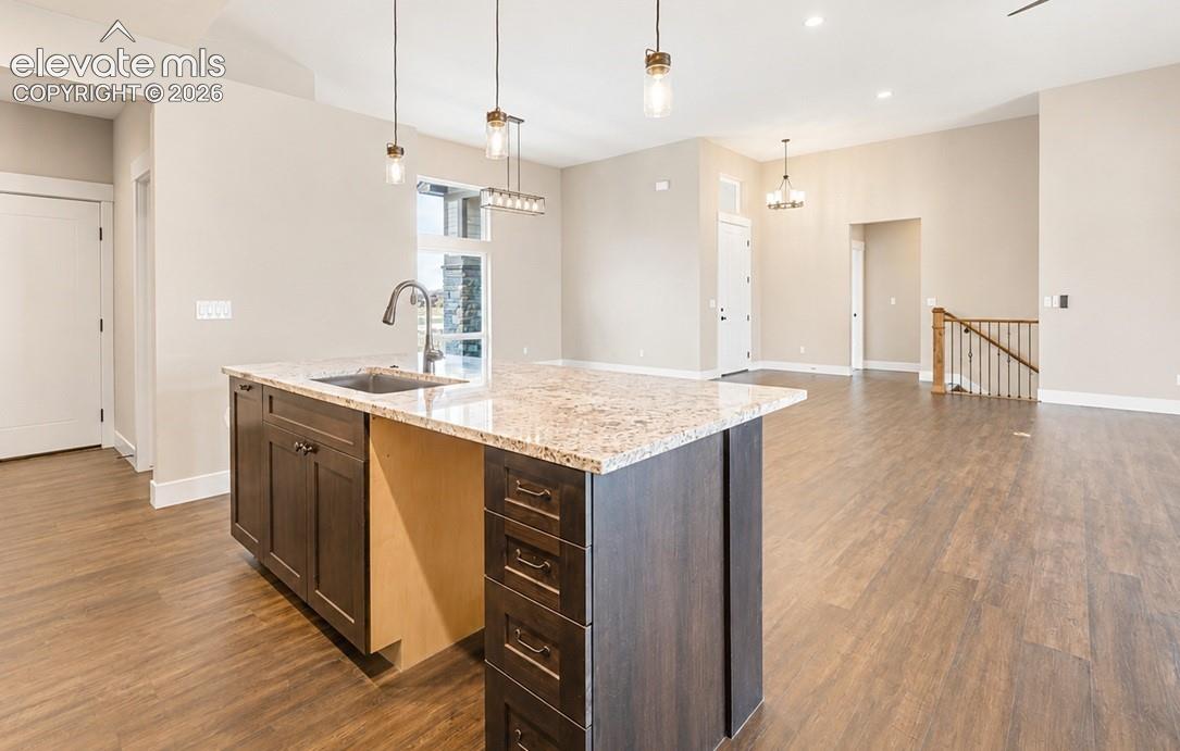 Kitchen island with granite-style countertop, undermount sink, and dark wood-finish cabinetry