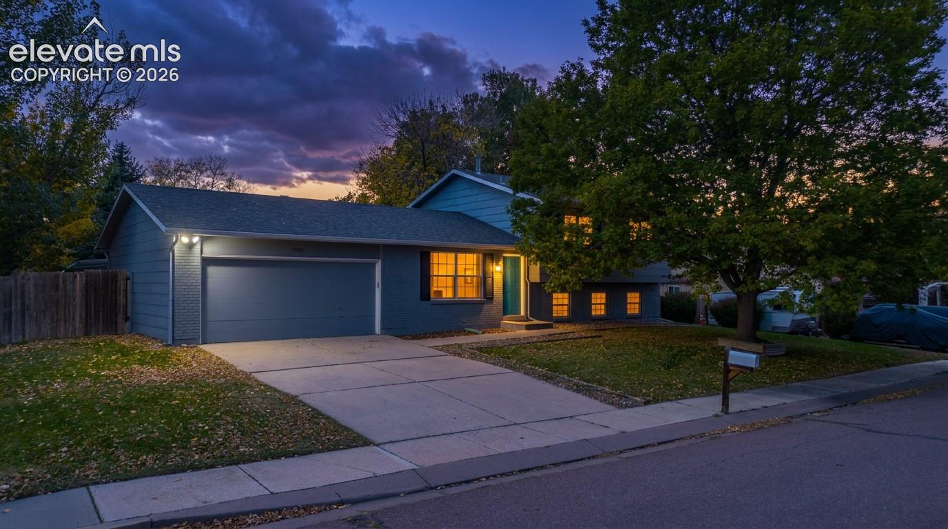 Exterior facade featuring horizontal siding, an attached two-car garage, concrete driveway, and multi-pane windows with dark shutters