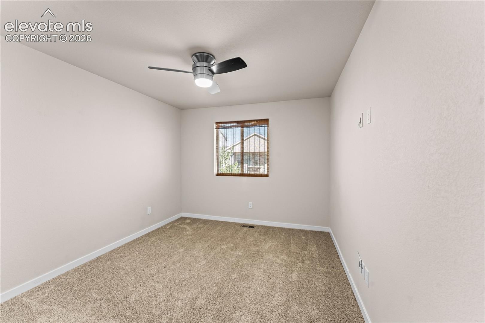 Interior room featuring neutral wall paint, wall-to-wall carpeting, and a brushed-nickel ceiling fan with integrated lighting