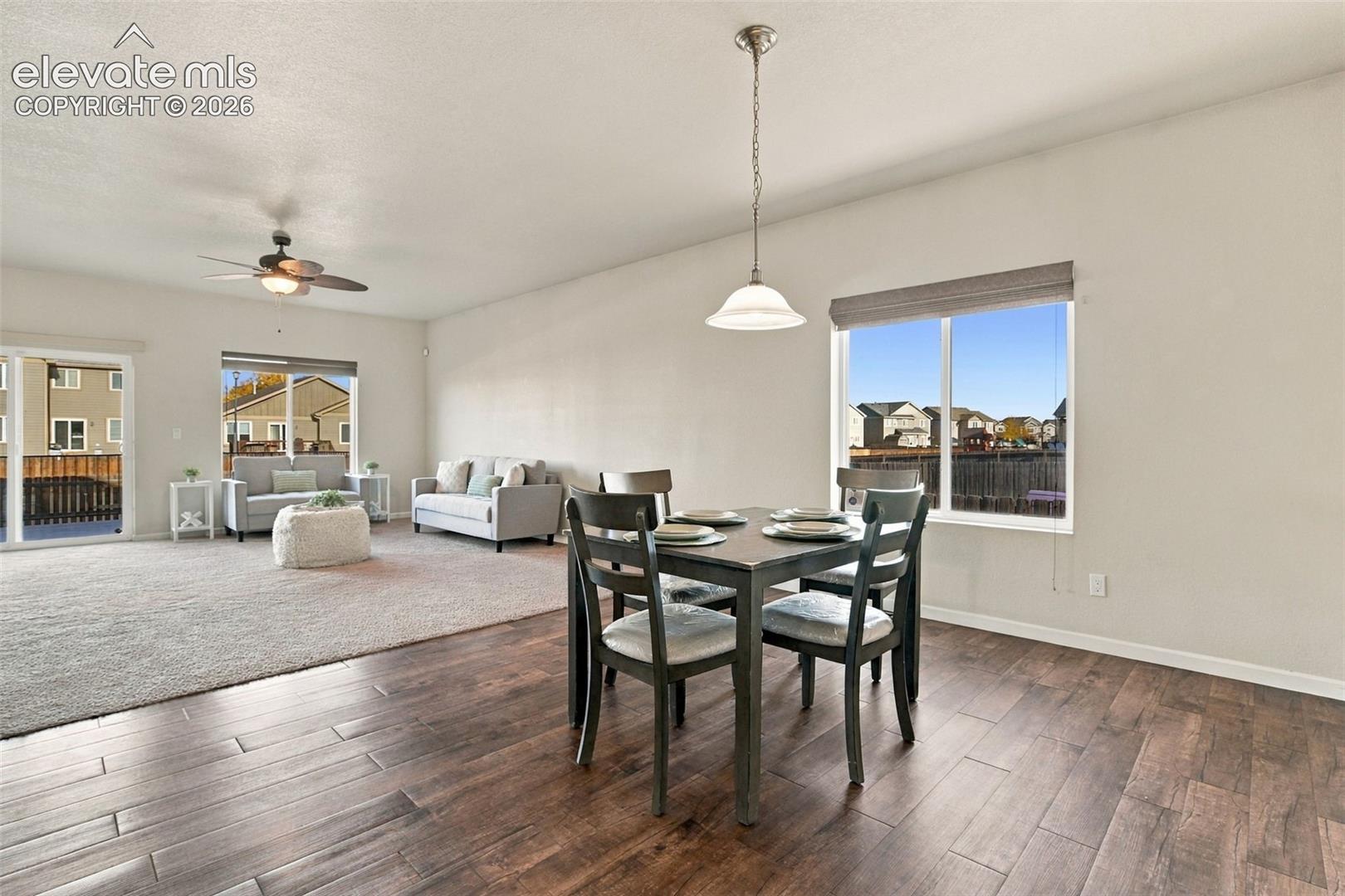 Dining area featuring wood-finish flooring, a pendant light fixture, and large windows with integrated blinds