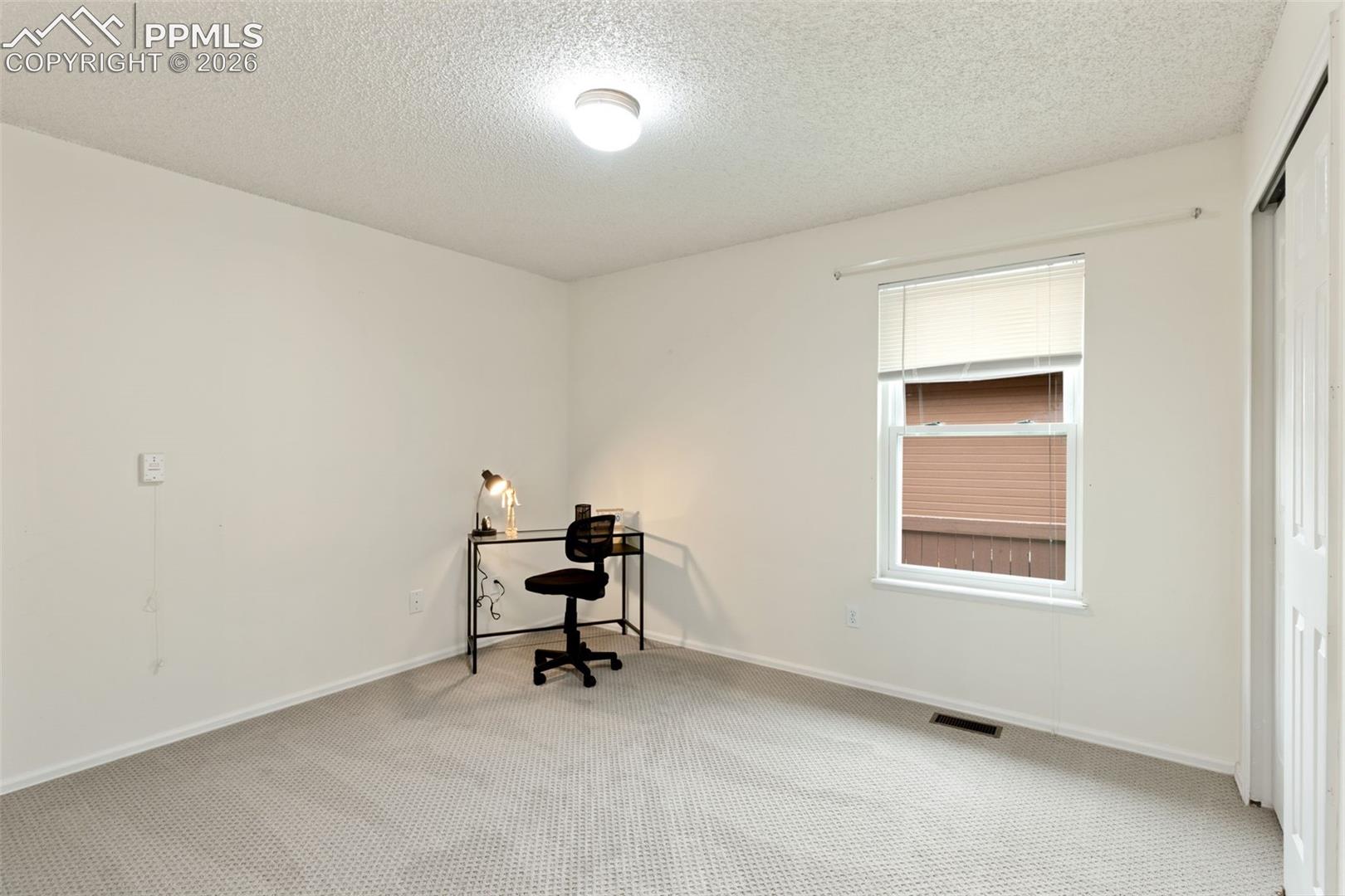 The property features light-colored carpet flooring, a window with blinds, and a ceiling light fixture