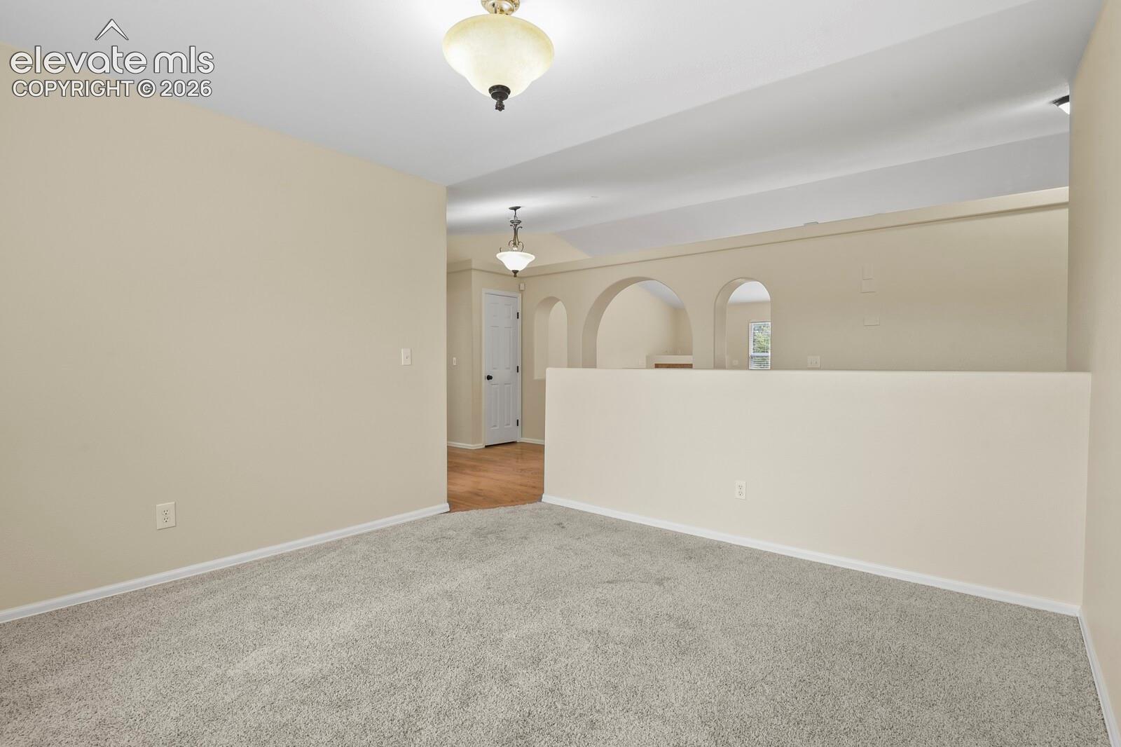 Carpeted interior space with a vaulted ceiling and a built-in half wall
