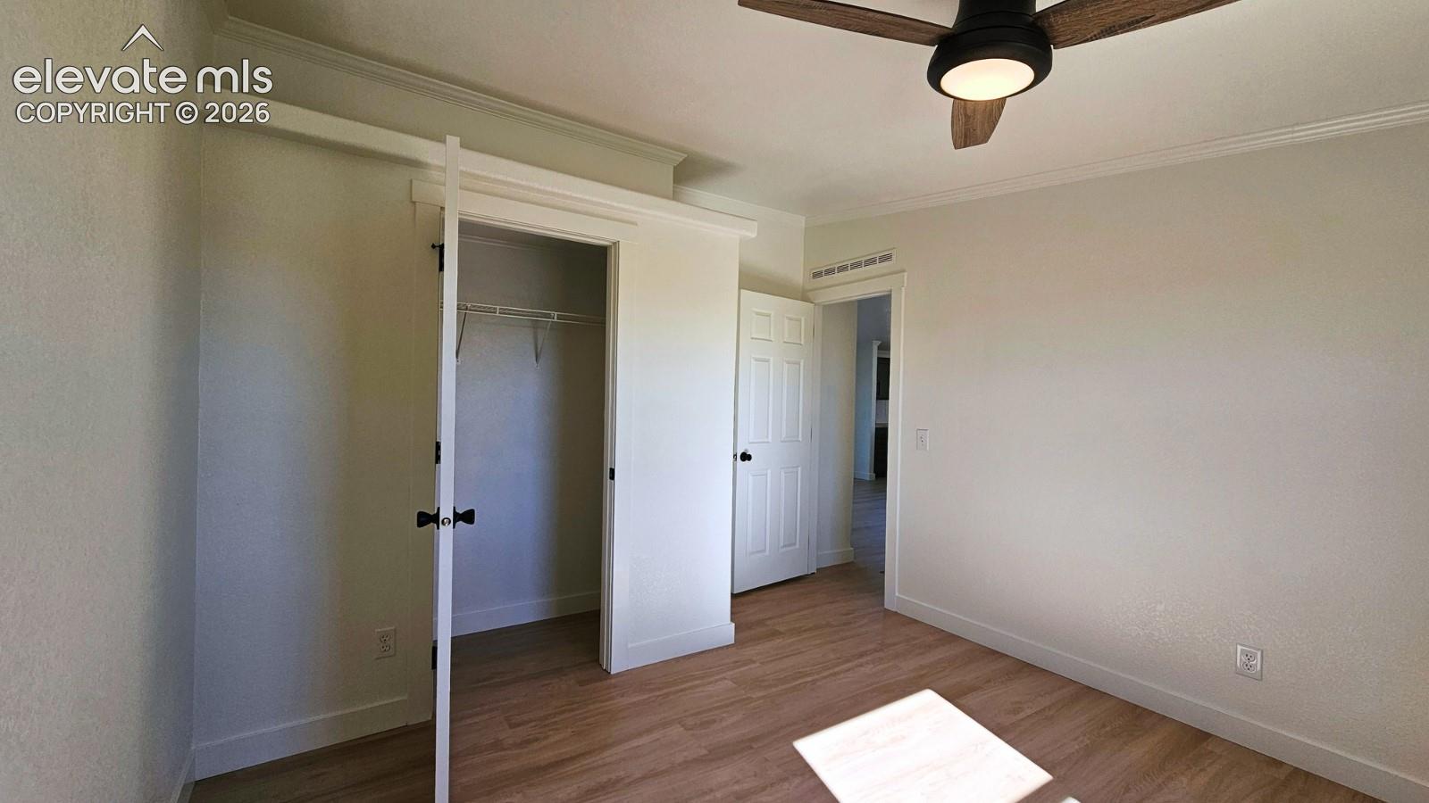 Wood-finish flooring, ceiling fan with integrated lighting, and crown molding