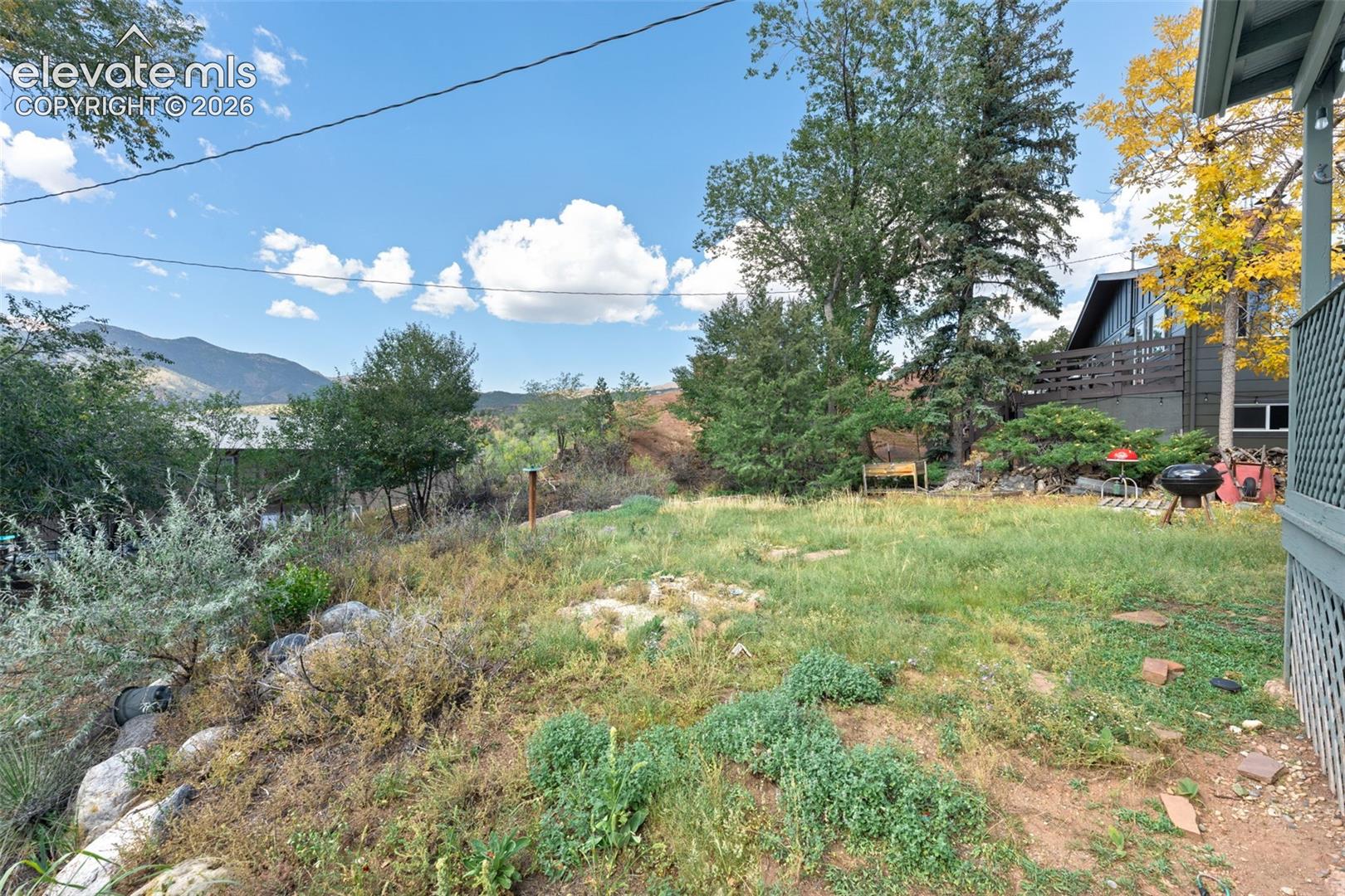 Expansive outdoor space featuring a sloped natural landscape, mature trees, and a distant mountain backdrop