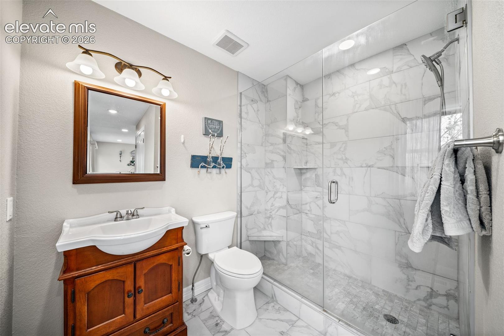 Contemporary bathroom featuring a glass-enclosed shower with large format tile surround, a built-in shower bench, and recessed lighting