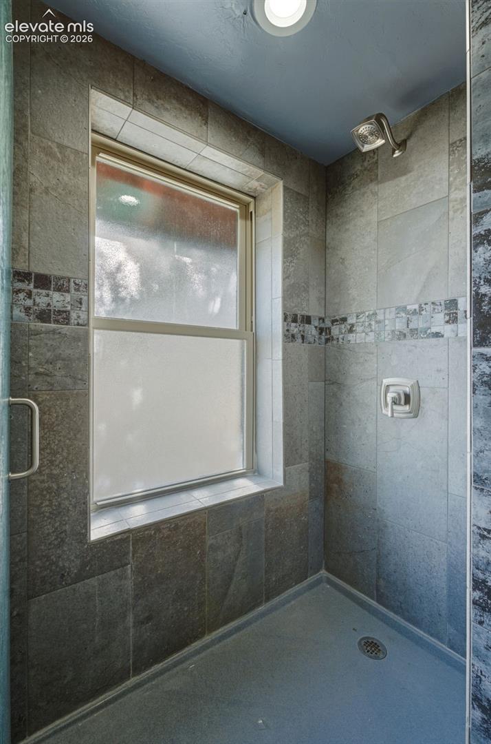 Tiled shower enclosure featuring a frosted window, decorative mosaic tile accents, and a built-in recessed light fixture