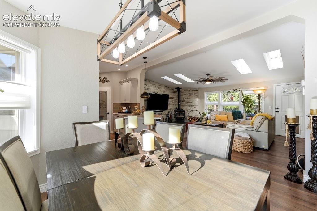 Open-concept living space with wood-finish flooring, vaulted ceilings, and skylights