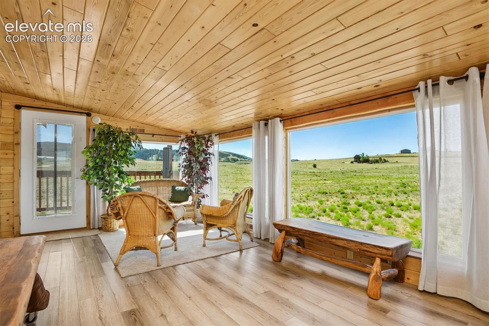 Sunroom featuring expansive windows, wood-finish flooring, and a natural wood plank ceiling