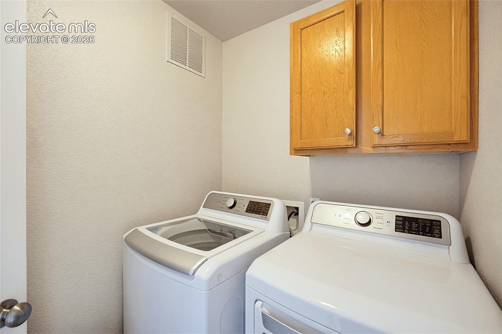 Laundry space featuring wall-mounted light wood-finish cabinetry and dedicated hookups