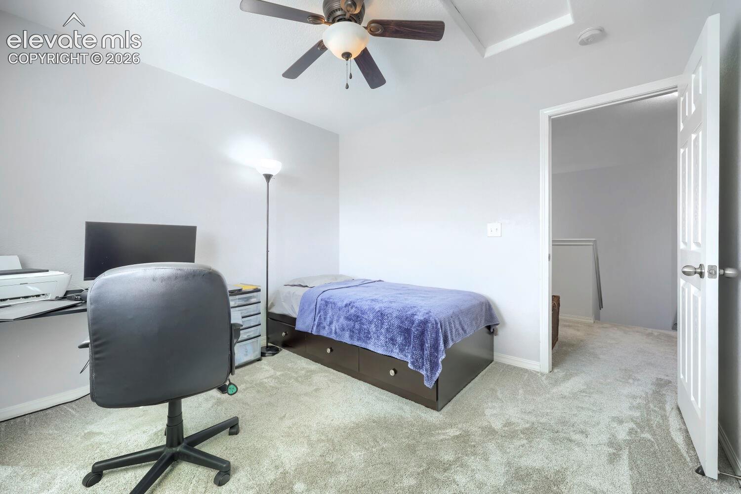 Neutral-toned carpeting, tray ceiling, and ceiling fan with integrated light fixture