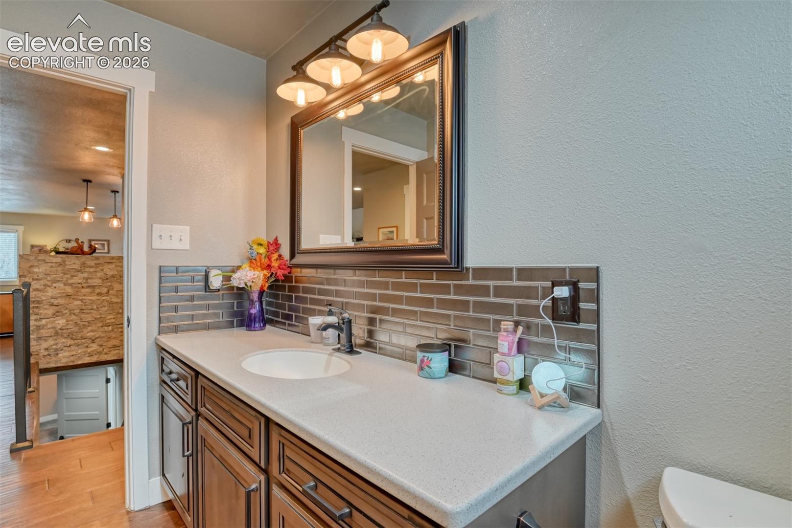 Bathroom featuring tasteful backsplash, vanity, a textured wall, and light wood-type flooring