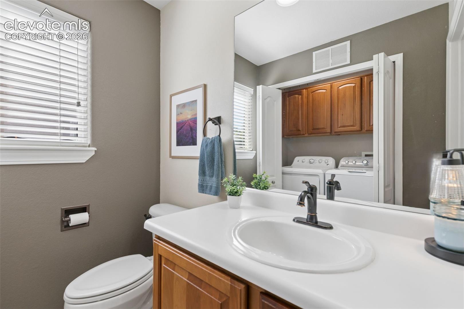 Bathroom featuring a single-sink vanity with wood-finish cabinetry, a white countertop, and a black-finish faucet