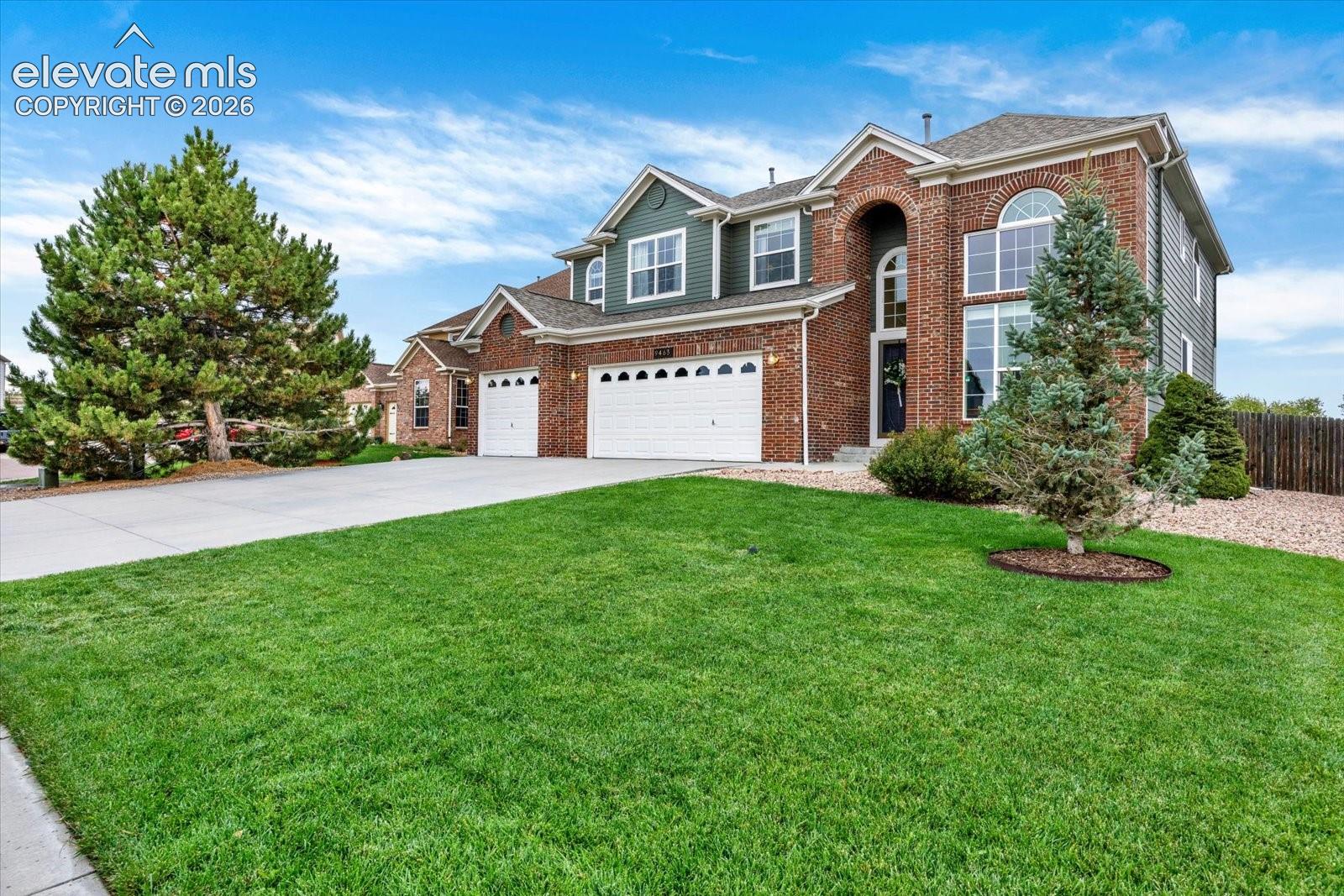 Two-story brick exterior featuring an arched entry, multi-gabled roofline, three-car garage, and arched windows