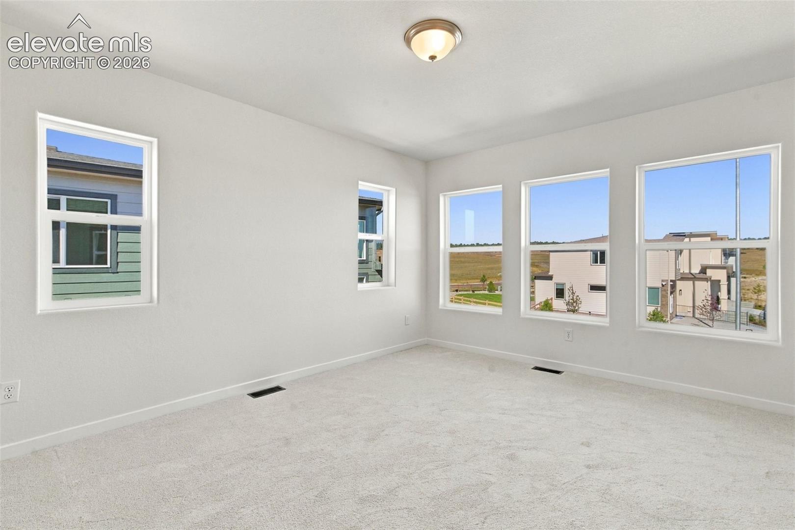 Recessed lighting with a semi-flush ceiling fixture, neutral carpeting, and multiple windows
