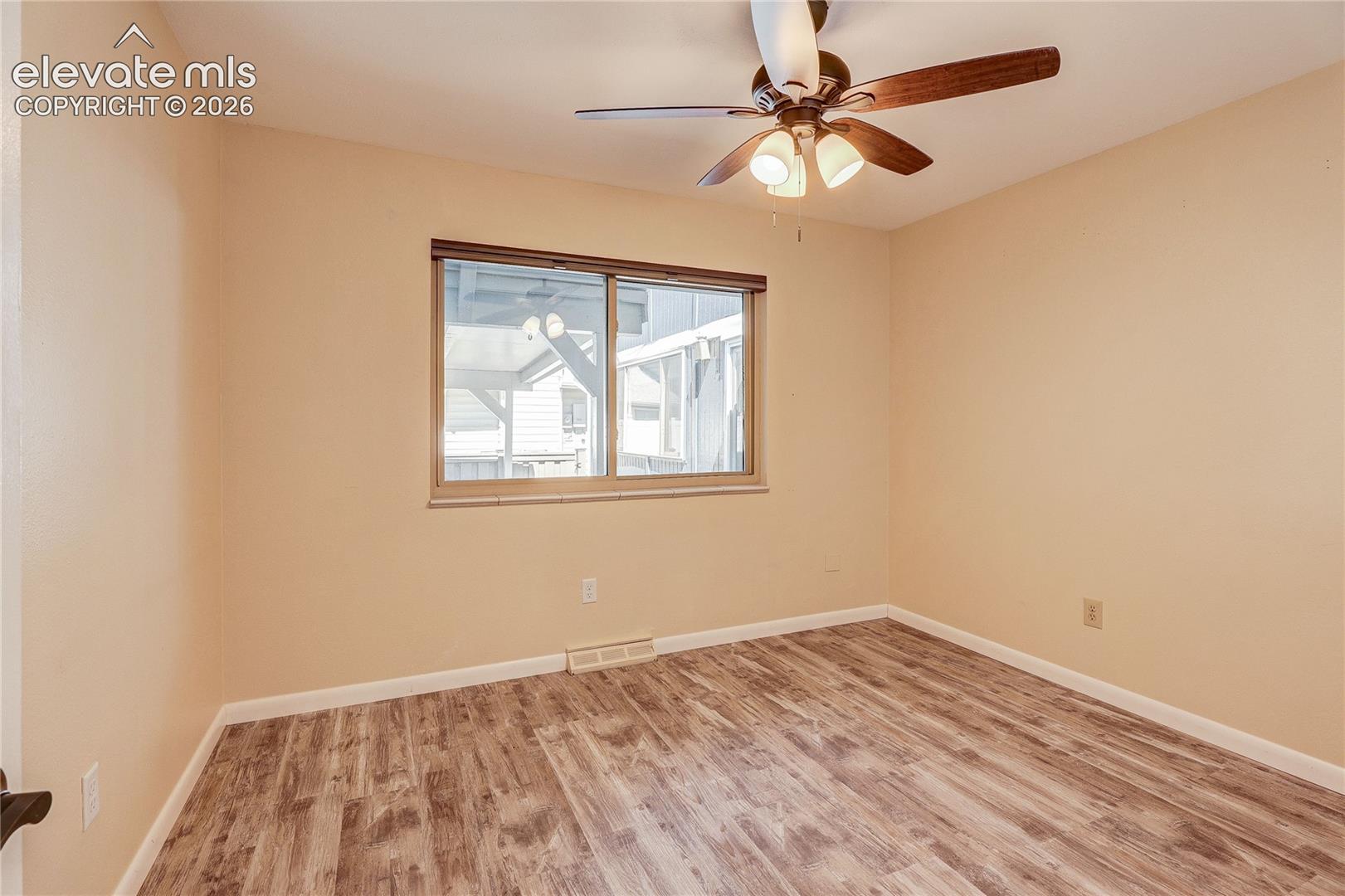 Interior room featuring wood-finish flooring, a ceiling fan with integrated lighting, and a single-pane horizontal window