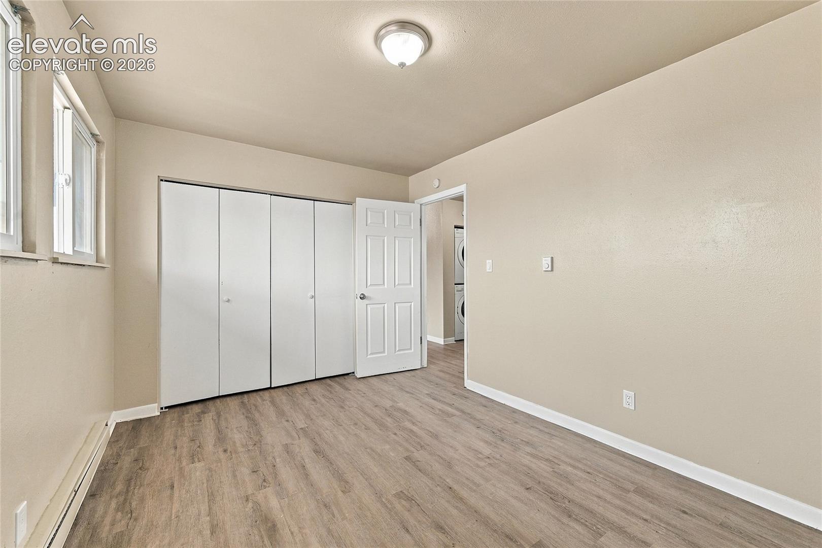 Room featuring wood-finish flooring, dual-pane windows, a ceiling-mounted light fixture, and floor-to-ceiling closet doors