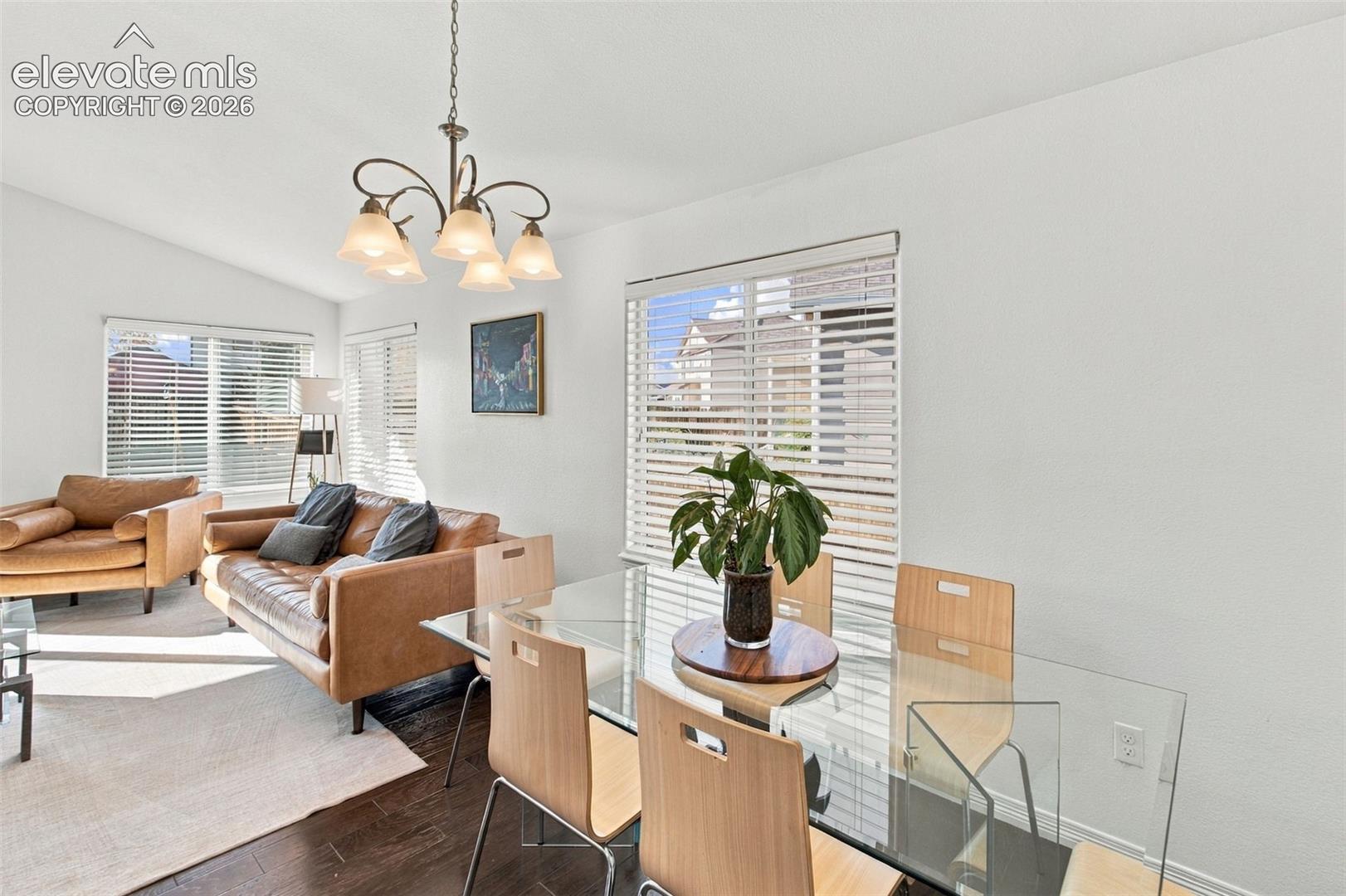 Vaulted ceiling, wood-finish flooring, and multi-light chandelier