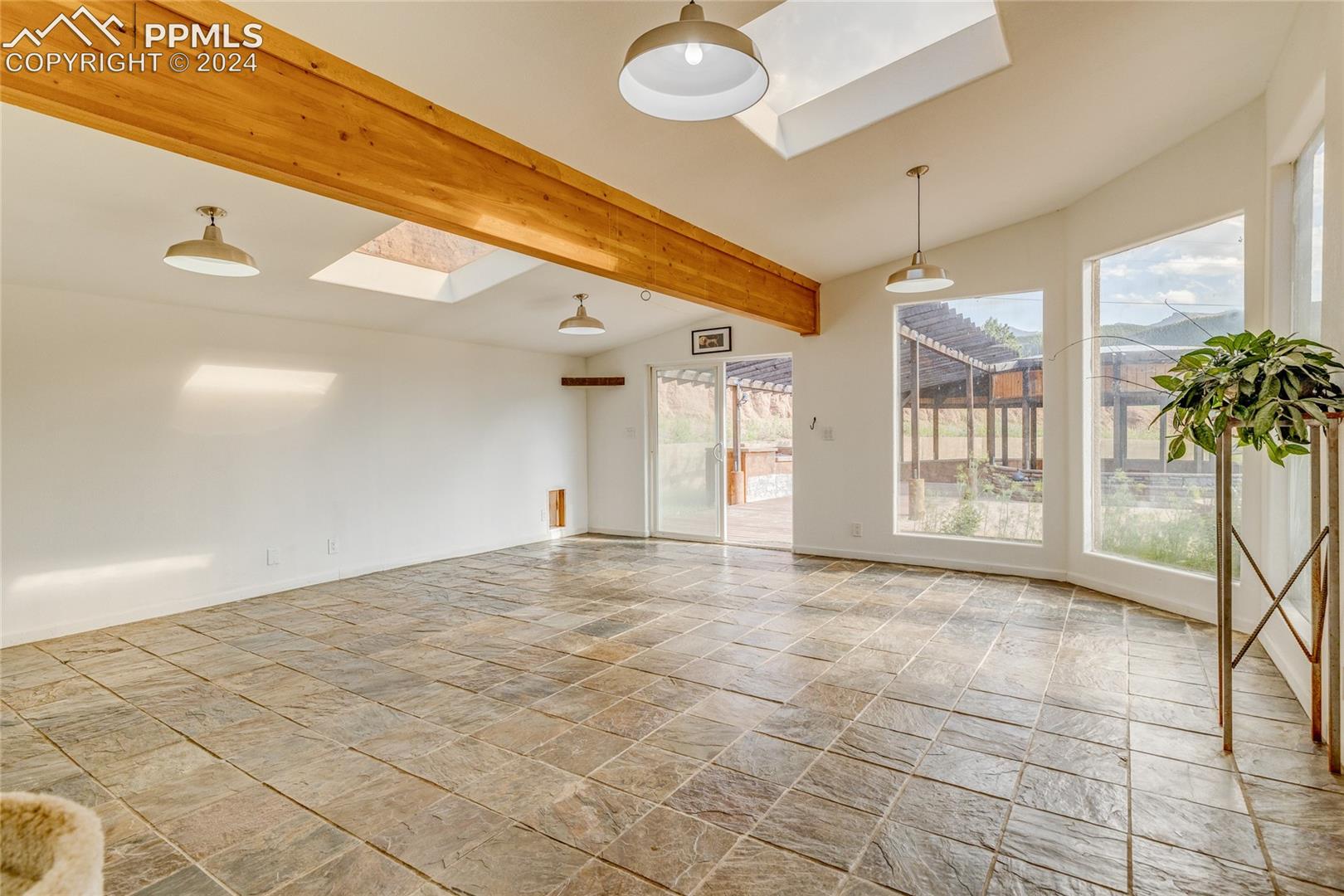Spare room featuring lofted ceiling with skylight and light tile flooring