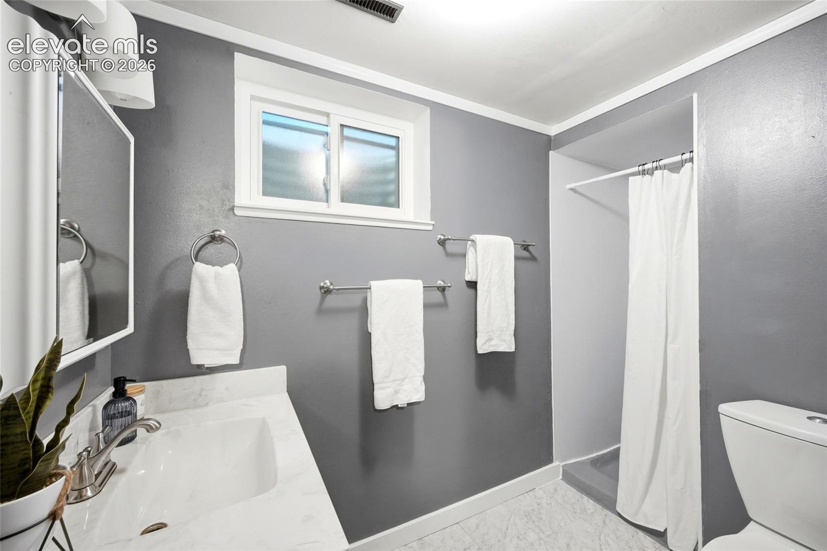 Bathroom featuring a stone-surface vanity with an integrated sink, polished chrome faucet, sliding window, and a built-in shower enclosure