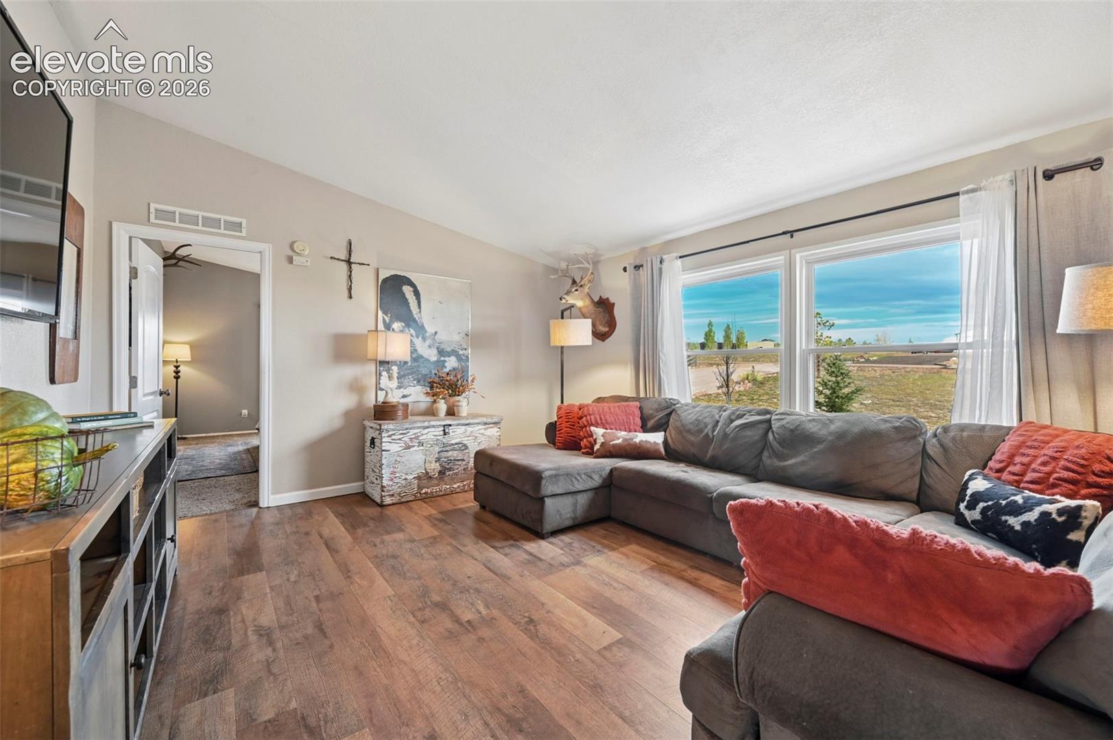 Vaulted ceilings, wood-finish flooring, and large windows providing natural light