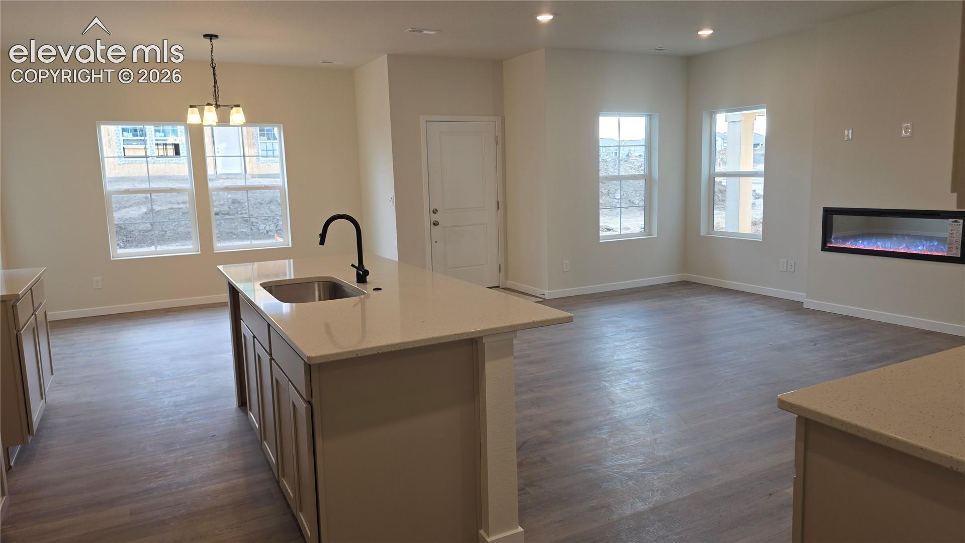 kitchen island and adjacent living room with peninsula island, sink faucet, recessed lights, and wall-mounted electric fireplace