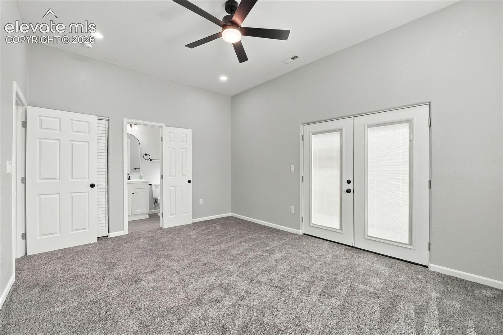Spacious carpeted room featuring a ceiling fan with integrated lighting, recessed lighting, and double panel doors