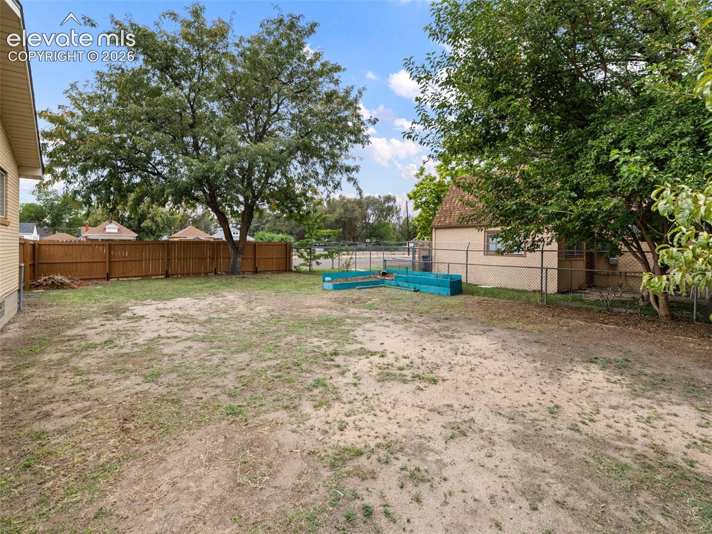 Expansive rear yard with a wood privacy fence and mature trees