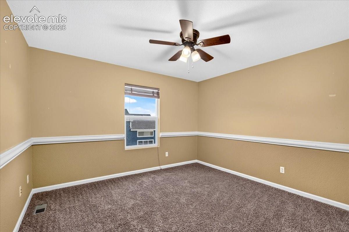 Ceiling fan with integrated lighting, window with blinds, wall with chair rail molding, and carpeted flooring