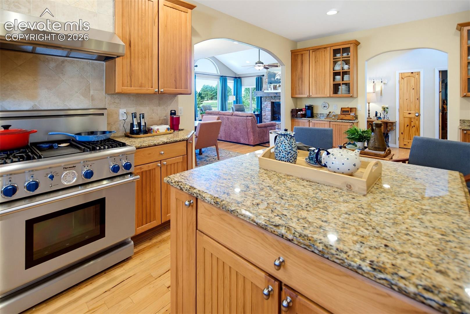 Kitchen features beautiful wood-finish cabinetry, stone countertops, and a professional grade Thermador gas range with matching hood