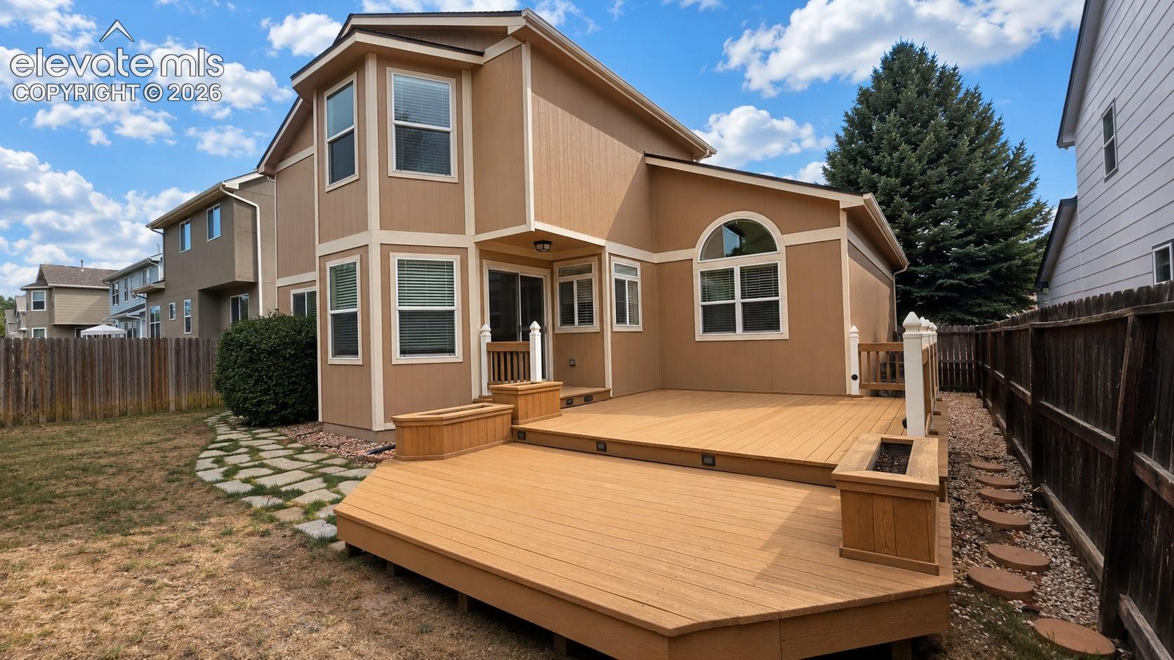 Multi-level composite deck with built-in planters, stone pathway, and privacy fencing