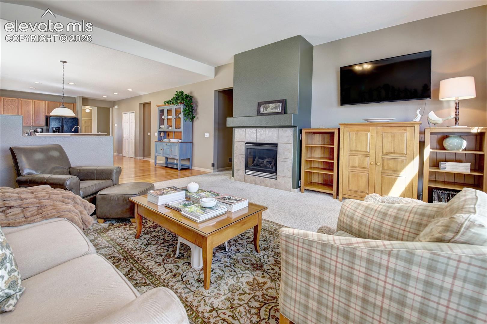 Fireplace with tile surround, wood-finish flooring, and open-concept layout