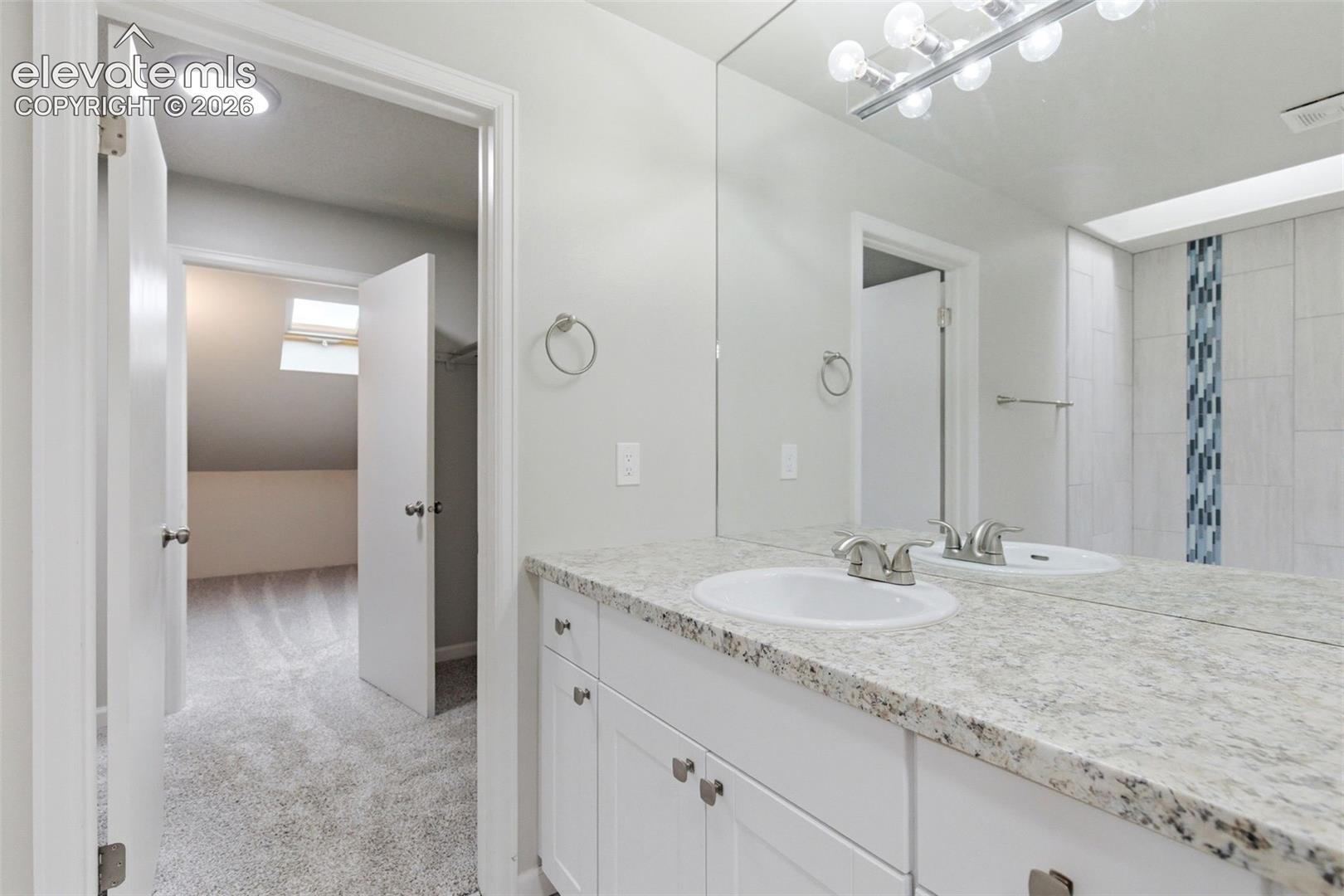 Bathroom vanity featuring a speckled countertop, integrated sink, and white cabinetry