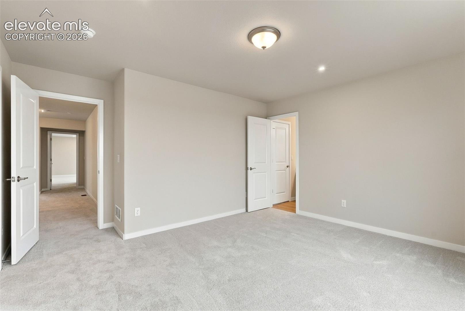 Neutral-toned interior space featuring wall-to-wall carpeting, paneled interior doors, and a flush-mount ceiling light fixture