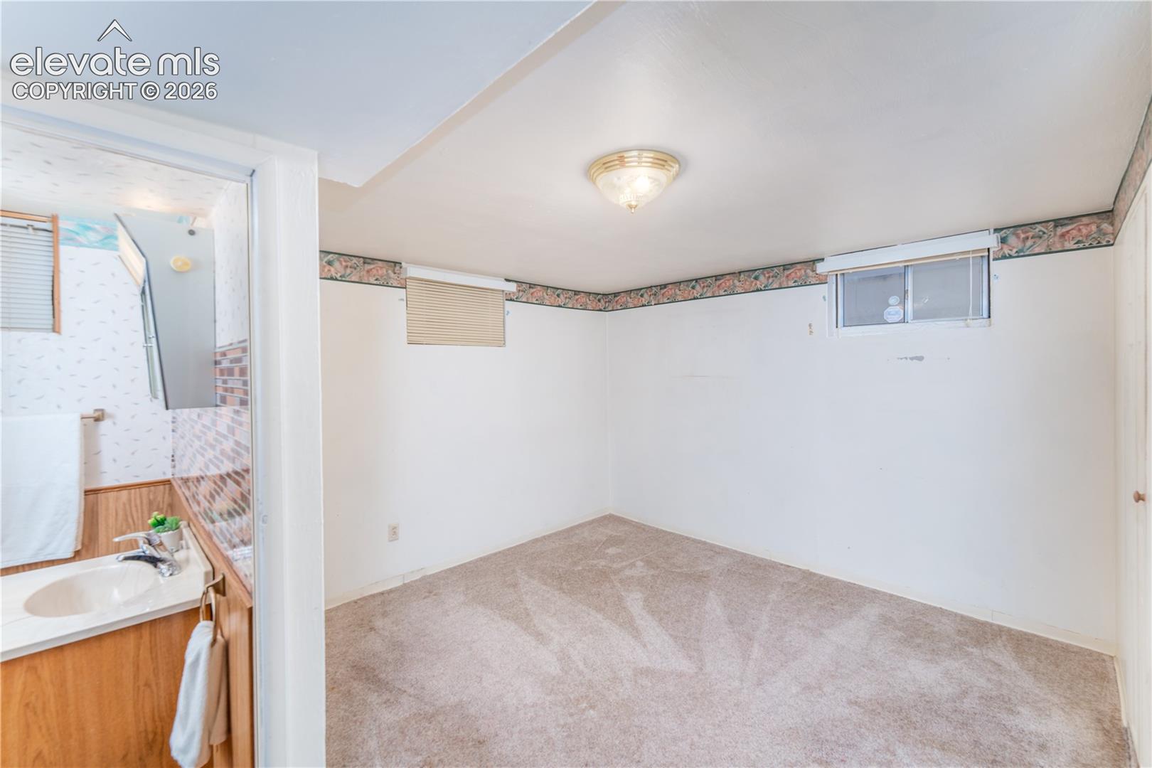 Carpeted room featuring a ceiling-mounted light fixture, and a window with blinds
