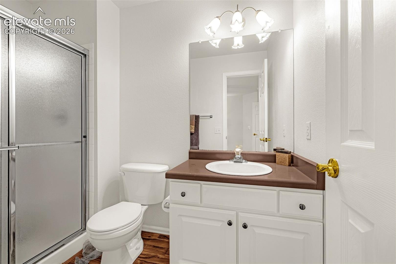 White vanity with dark hardware, brown countertop, and an oval sink