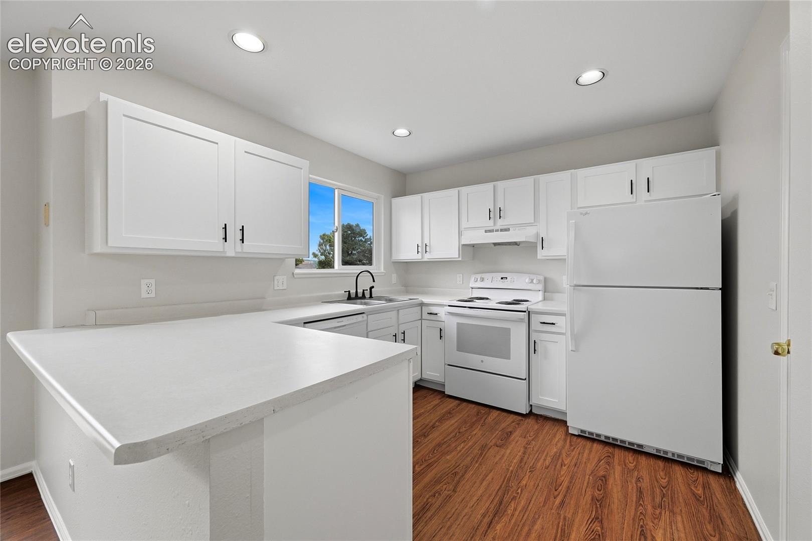 Kitchen featuring white cabinetry with dark hardware, solid surface countertops, wood-finish flooring, and recessed ceiling lighting