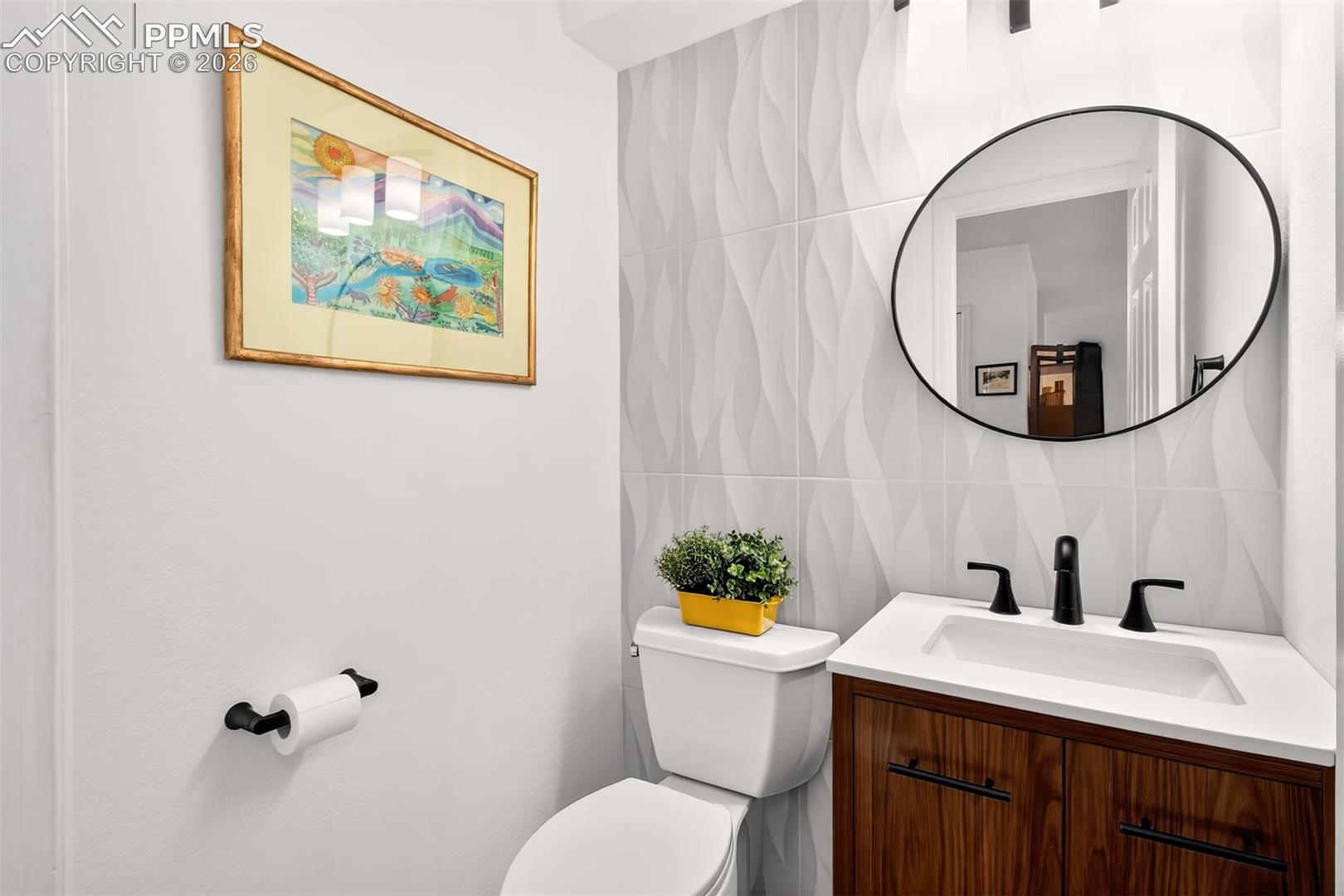 Updated main level half bath with new vanity and new decorative tiled wall.