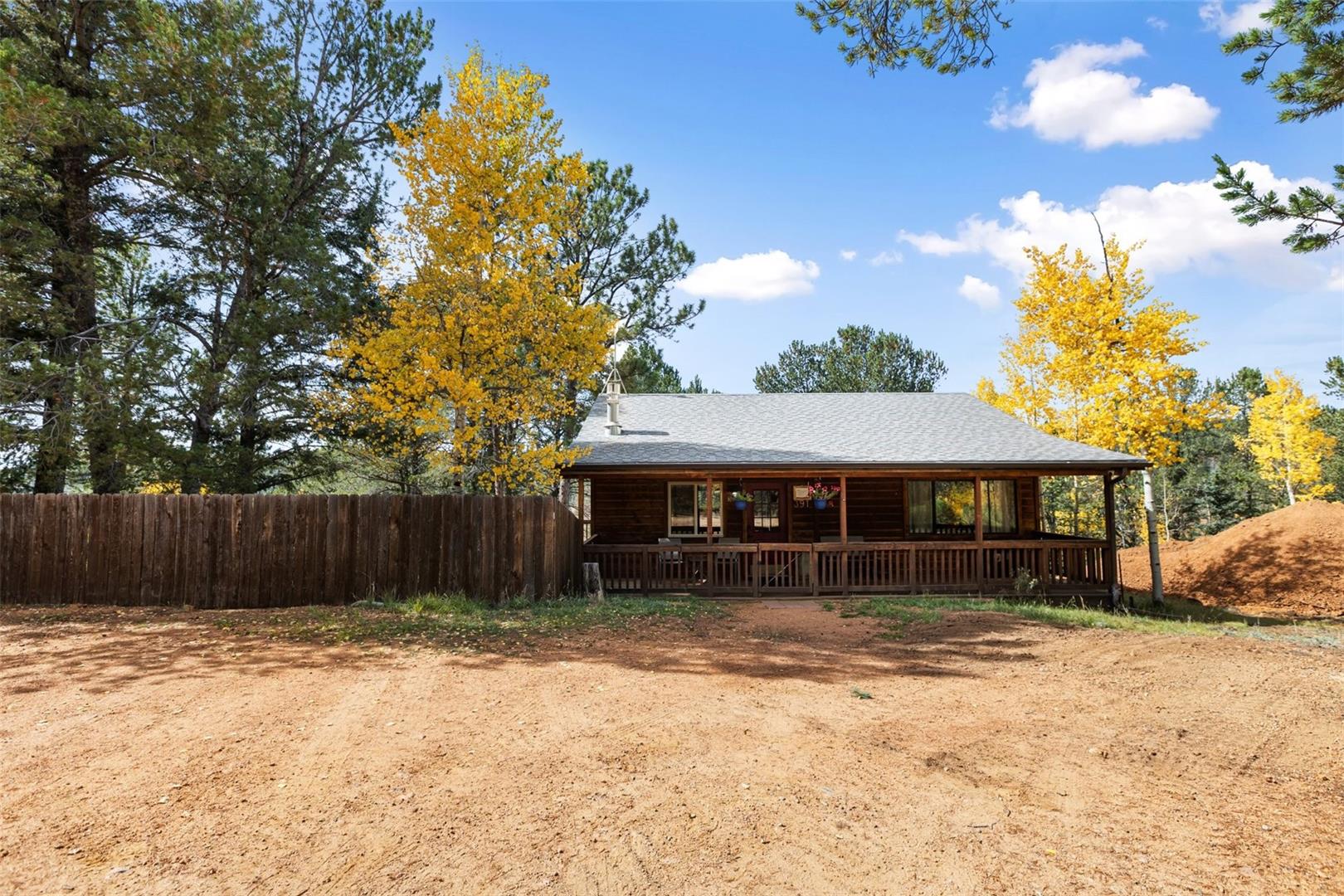 Log cabin exterior with a covered front porch, an asphalt shingle roof, and a wood fence