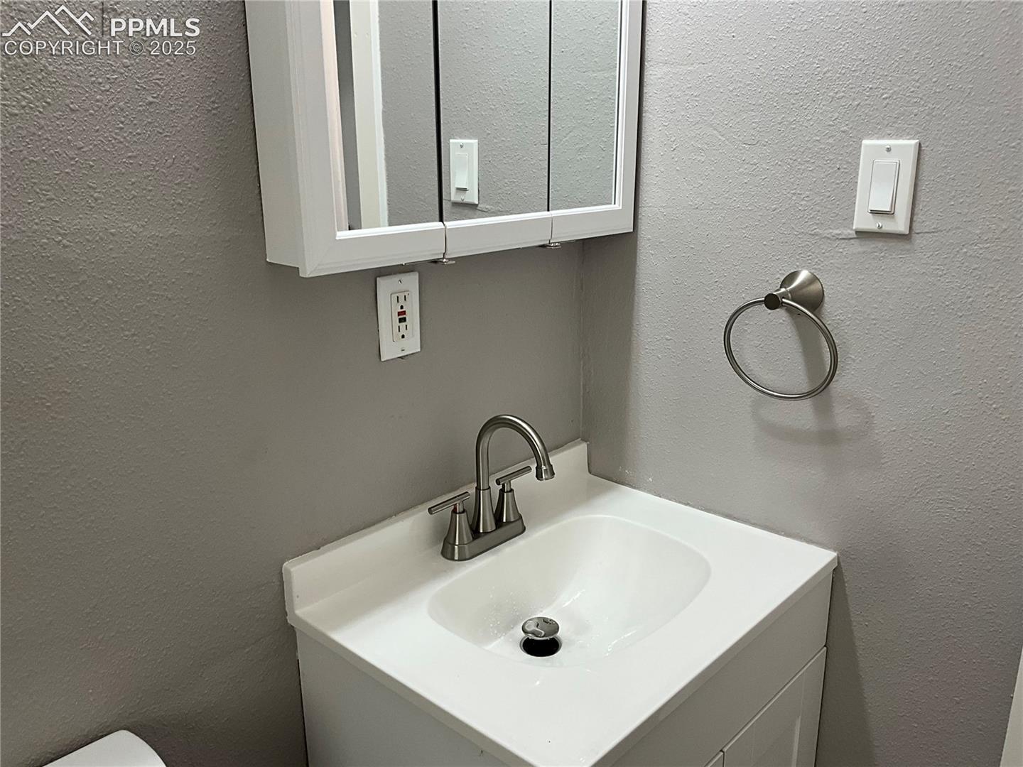 Bathroom featuring a textured wall and vanity