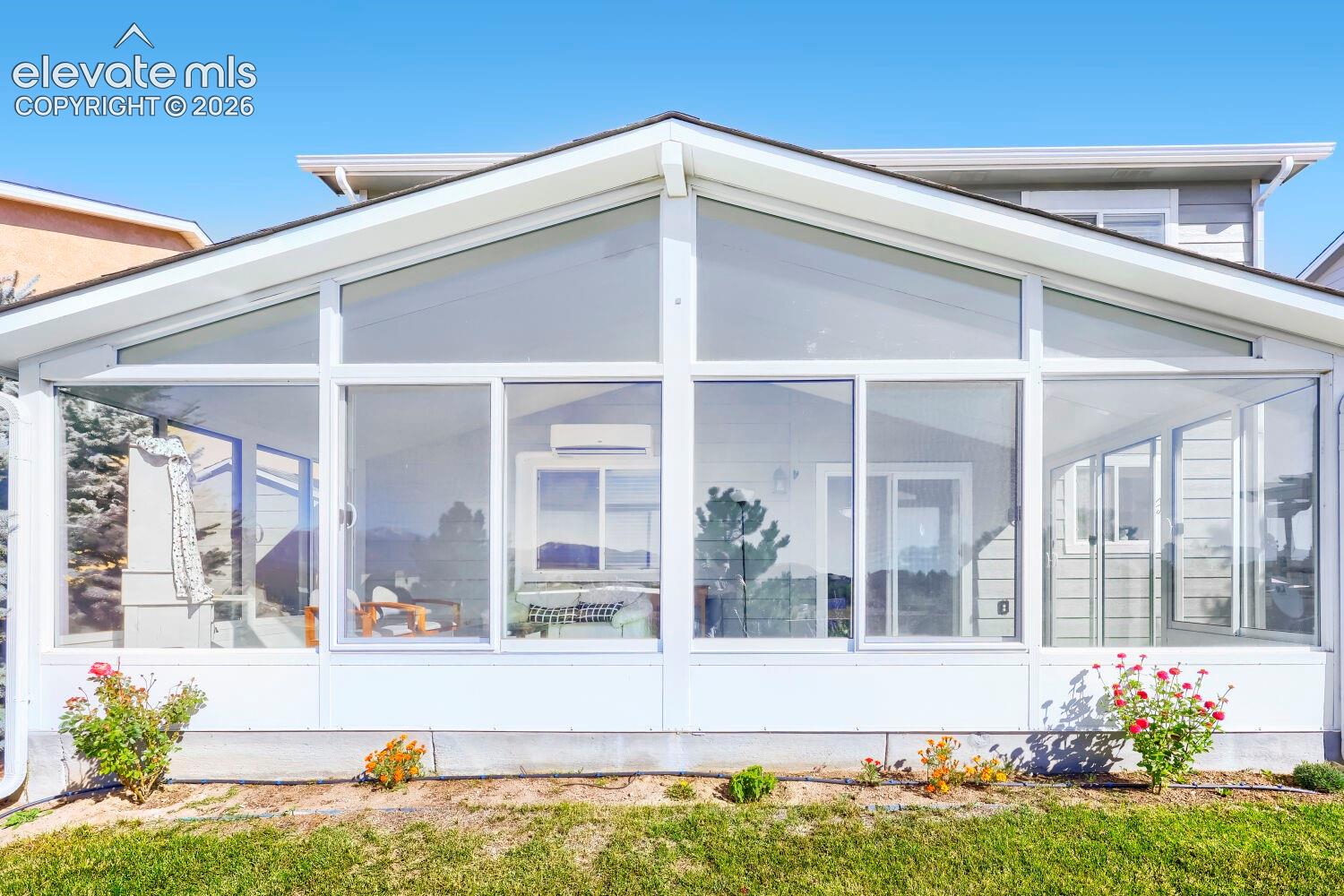 Sunroom featuring a vaulted ceiling, floor-to-ceiling windows, sliding glass door access, and white structural framing